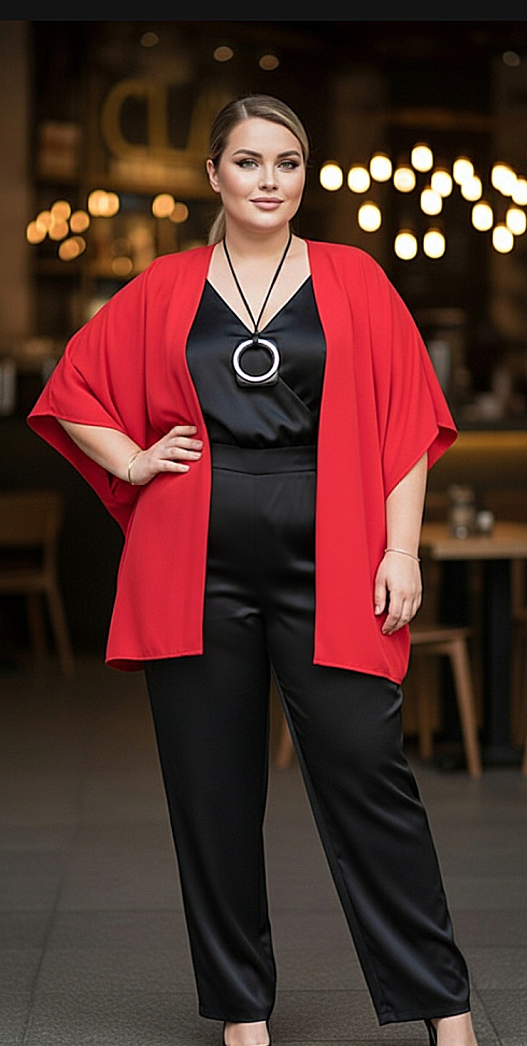Woman wearing a red cardigan over a black outfit with a blurred background