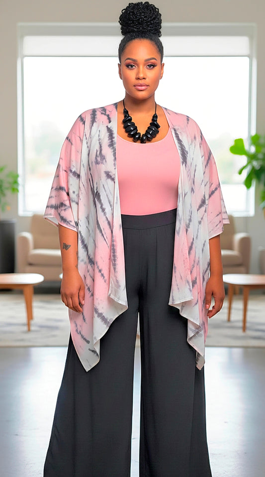 Woman wearing a pink kimono-style jacket over a pink top and black pants in a room with plants and furniture.