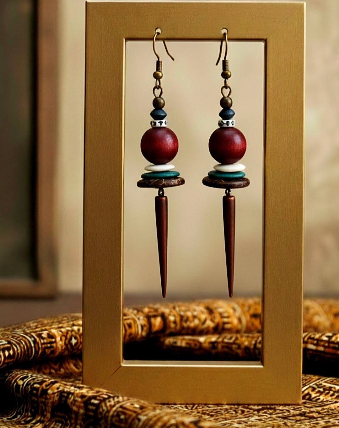 Pair of spike earrings with maroon and brown beads in a gold frame.