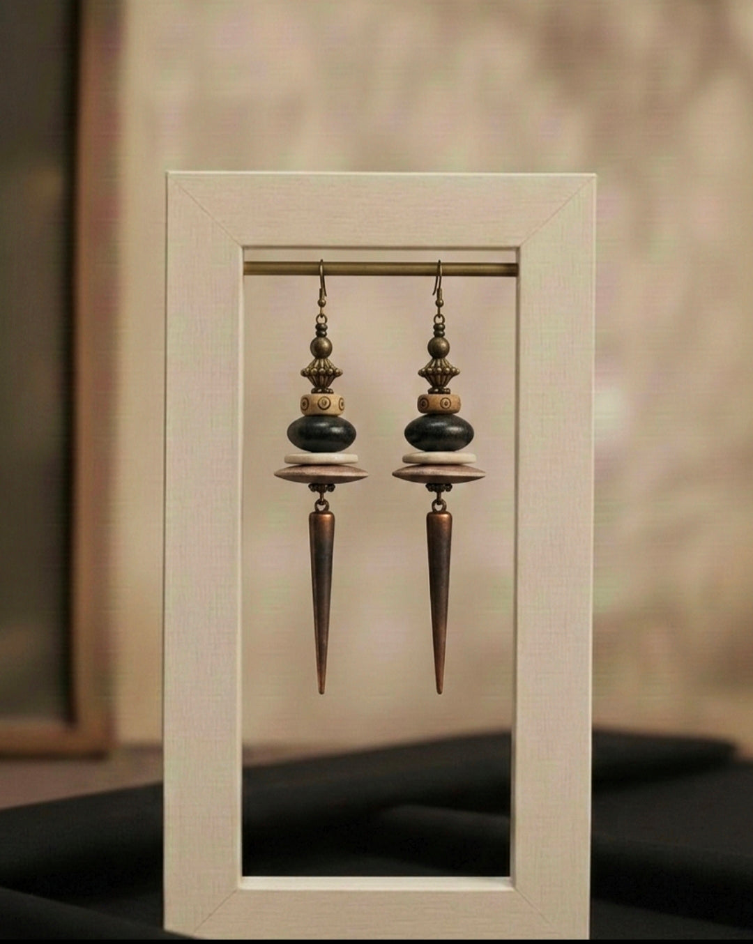Pair of ornate earrings displayed in a white frame against a neutral background