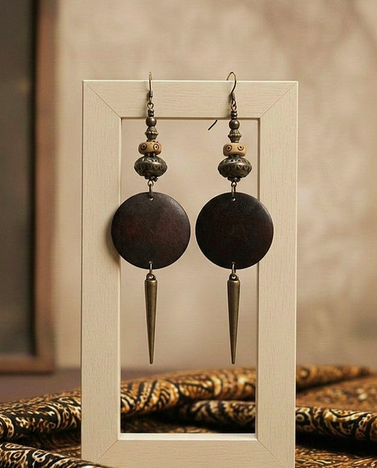 Pair of ornate earrings with circular and spike designs displayed in a frame.