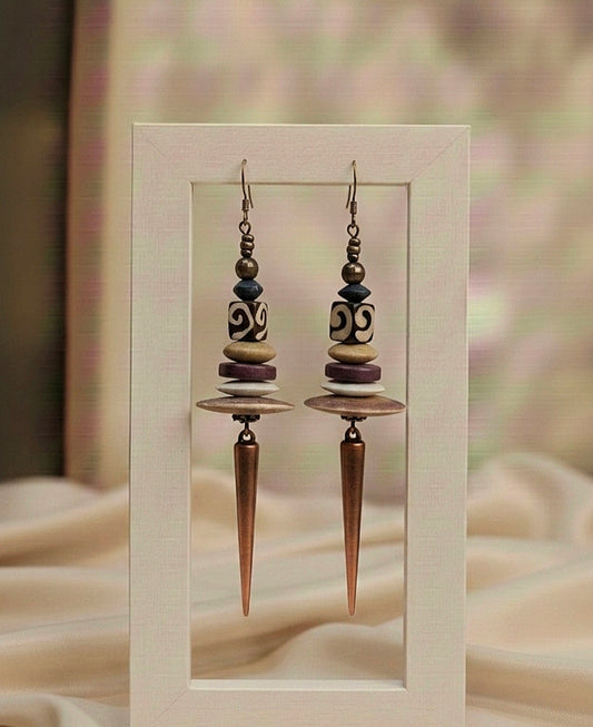 Pair of earrings with decorative beads and a pointed design in a frame.