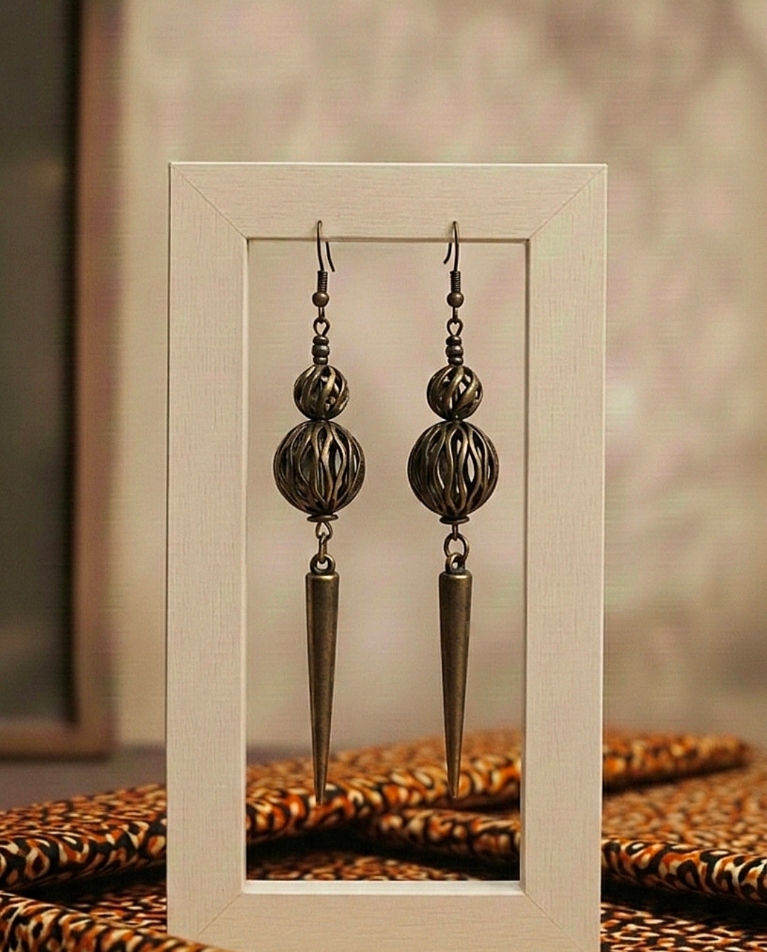 Pair of ornate earrings displayed in a white frame against a neutral background