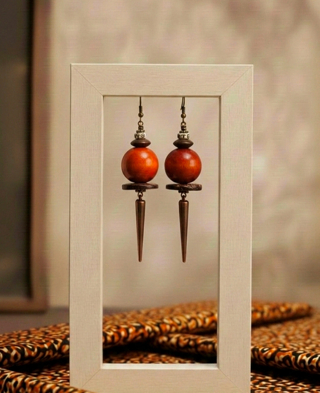 Pair of wooden earrings with long silver hooks displayed in a white frame.