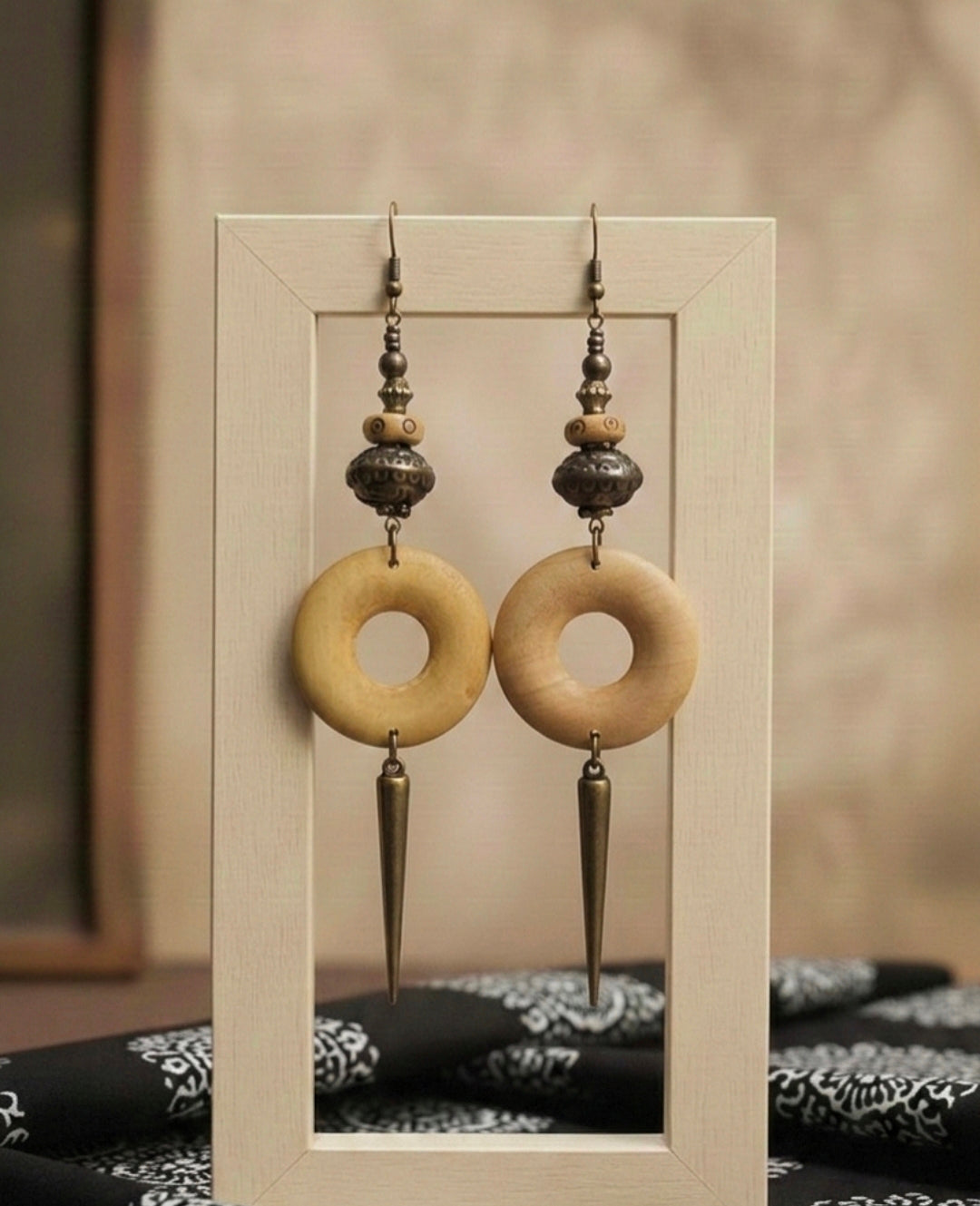 Pair of earrings with circular designs and hanging elements on a neutral background