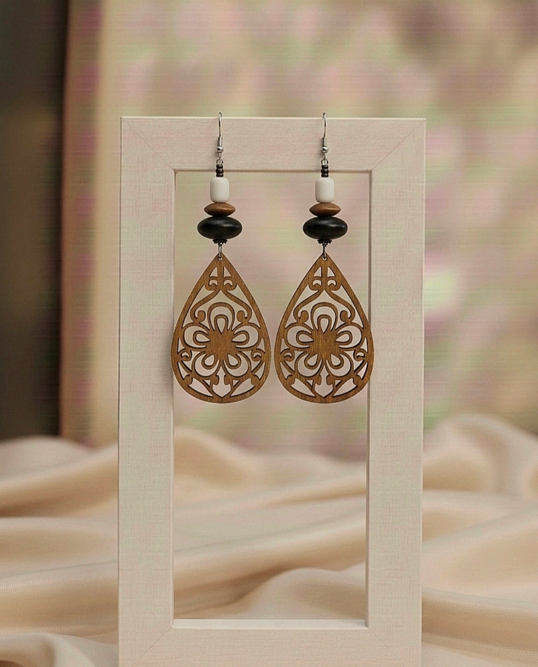 Pair of decorative earrings on a wooden stand with a soft blurred background