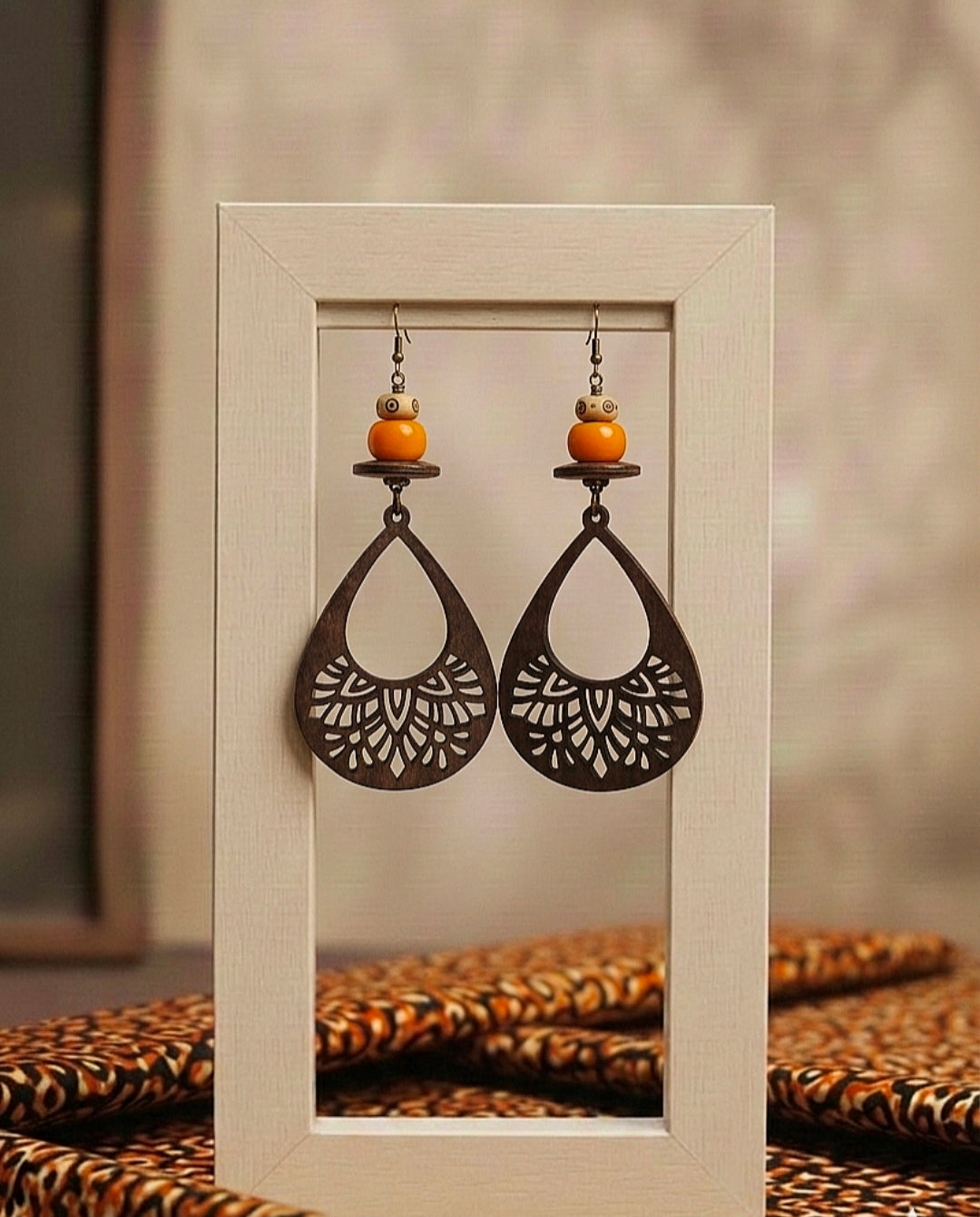 Pair of decorative earrings with intricate designs displayed in a frame.