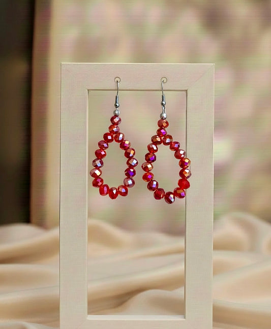 red Beaded earrings on a wooden stand with a blurred background