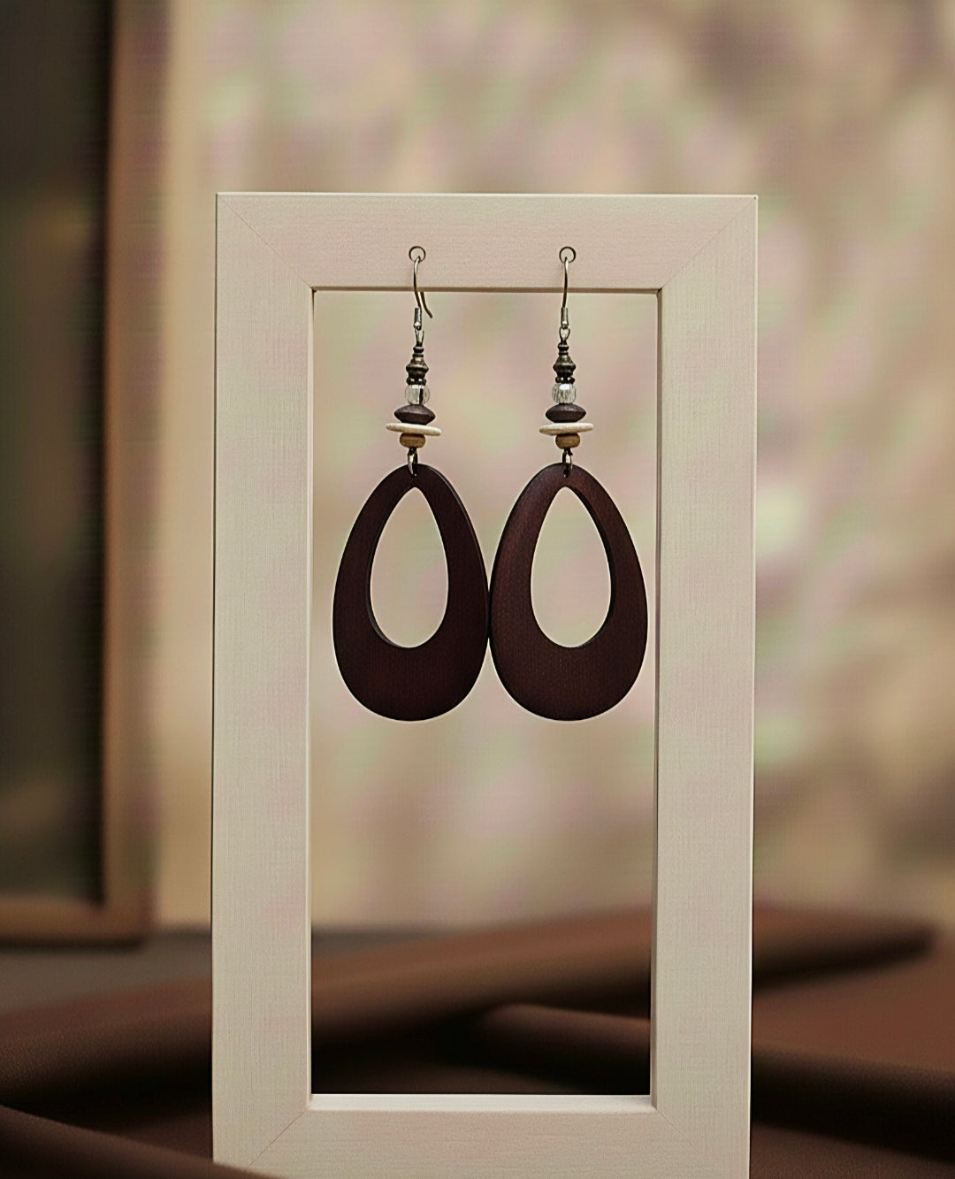Pair of brown earrings displayed in a white frame against a blurred background