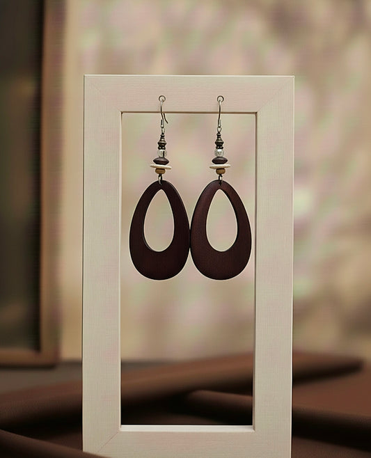Pair of brown earrings displayed in a white frame against a blurred background