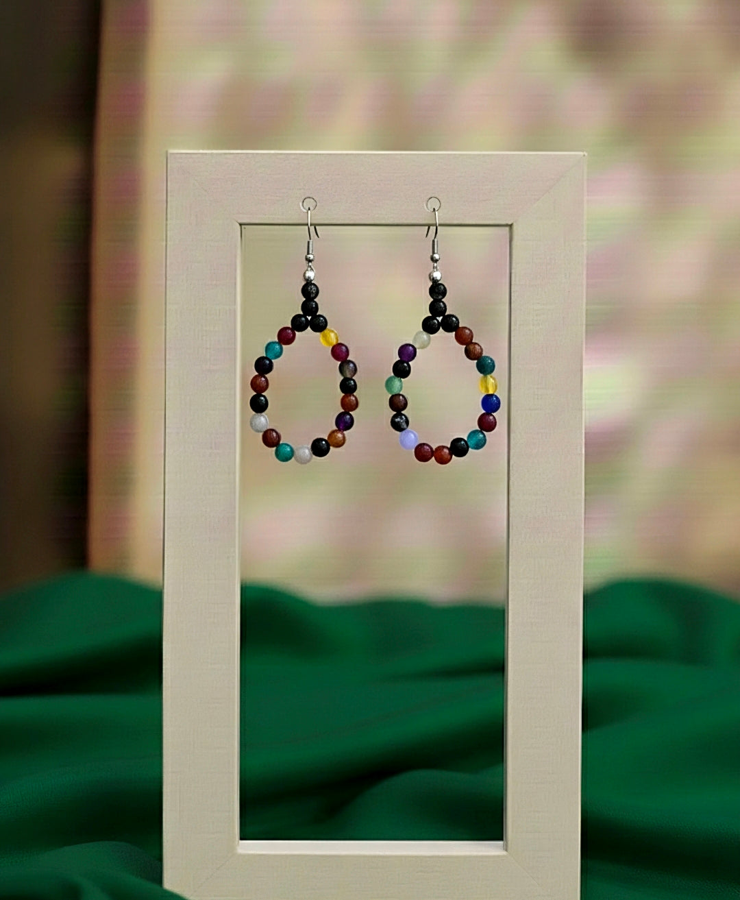 Colorful beaded earrings displayed on a stand with a blurred green background