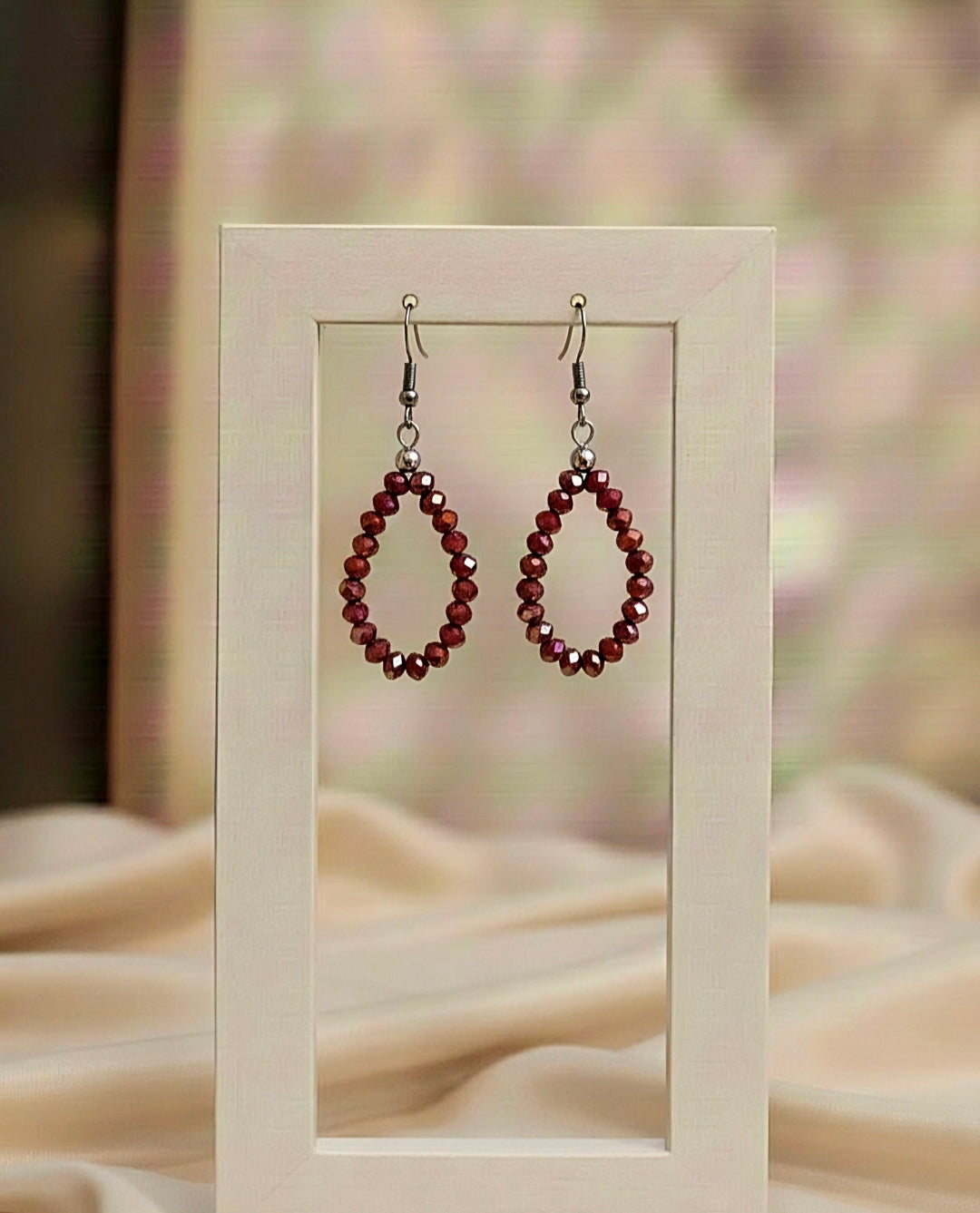 Pair of beaded earrings on a stand with a soft, blurred background