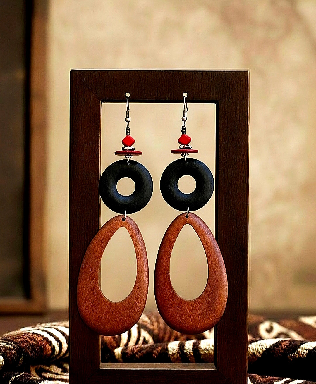 Pair of wood earrings with black and brown teardrop shapes on a wooden stand.