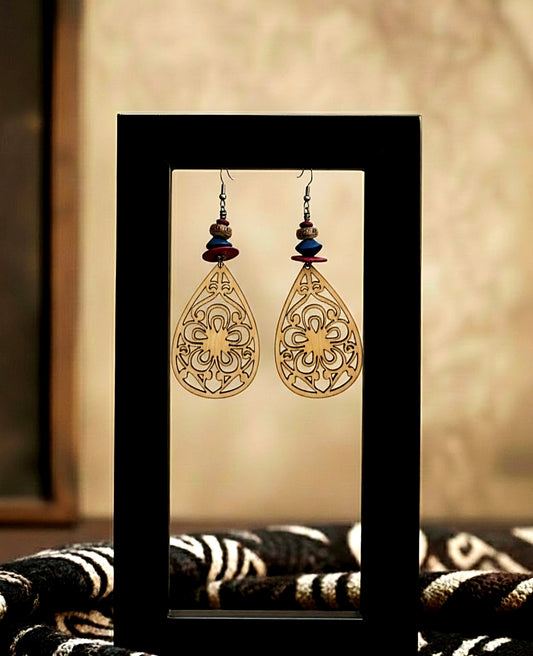 Pair of ornate earrings displayed in a black frame against a neutral background