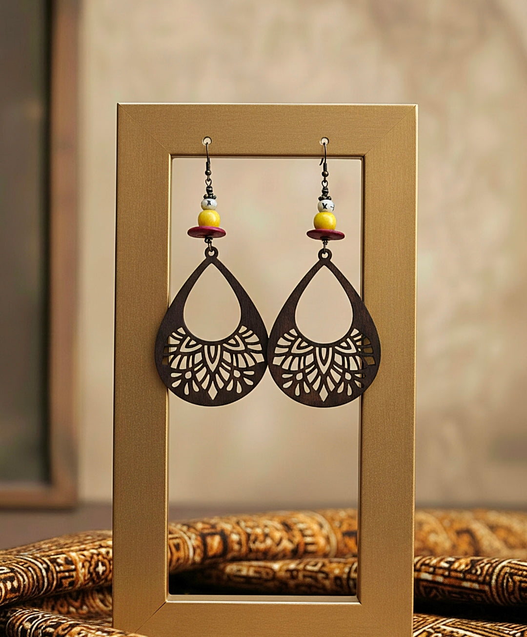Pair of earrings displayed in a gold frame against a neutral background
