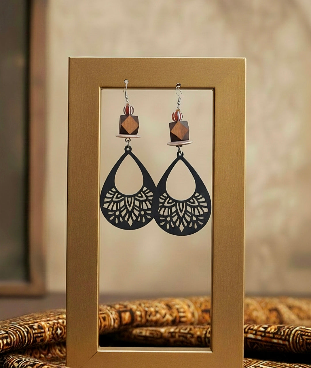 Pair of black earrings with intricate designs displayed in a gold frame.