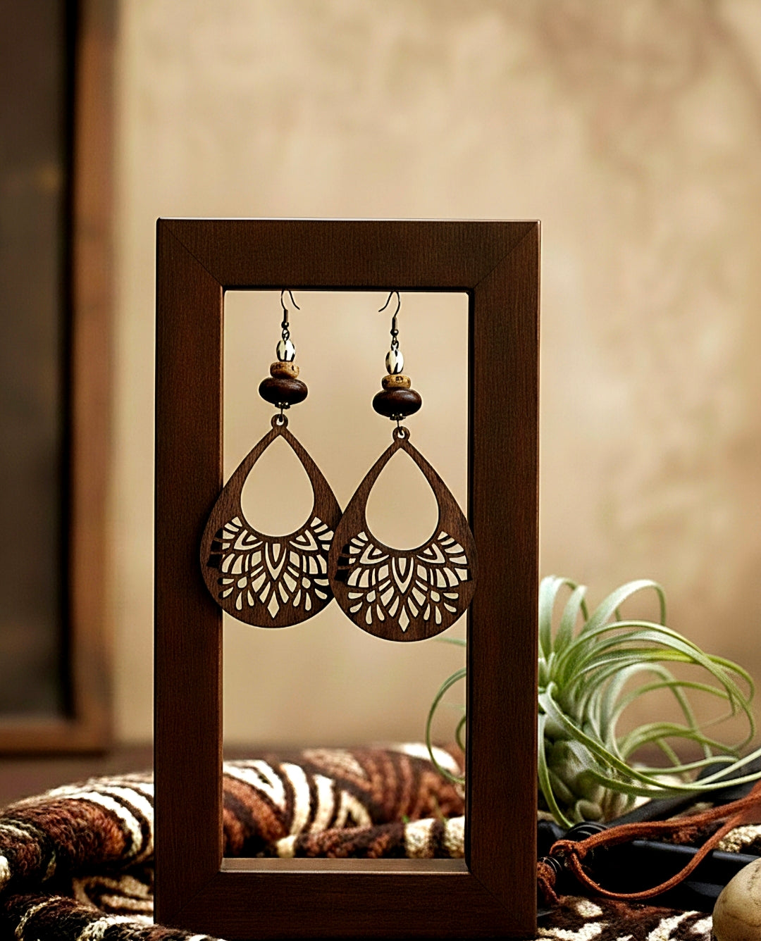 Wooden frame displaying a pair of intricate earrings with a blurred background
