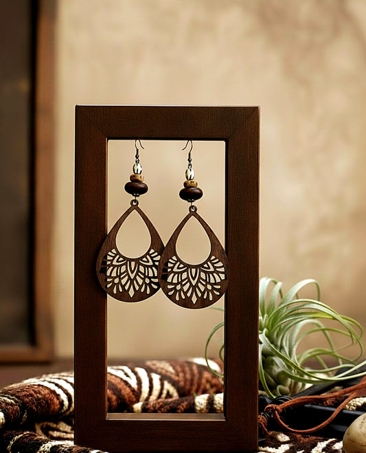 Wooden frame displaying a pair of intricate earrings with a blurred background