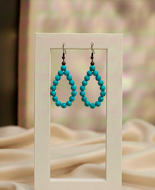 Turquoise beaded earrings displayed in a white frame with a soft background