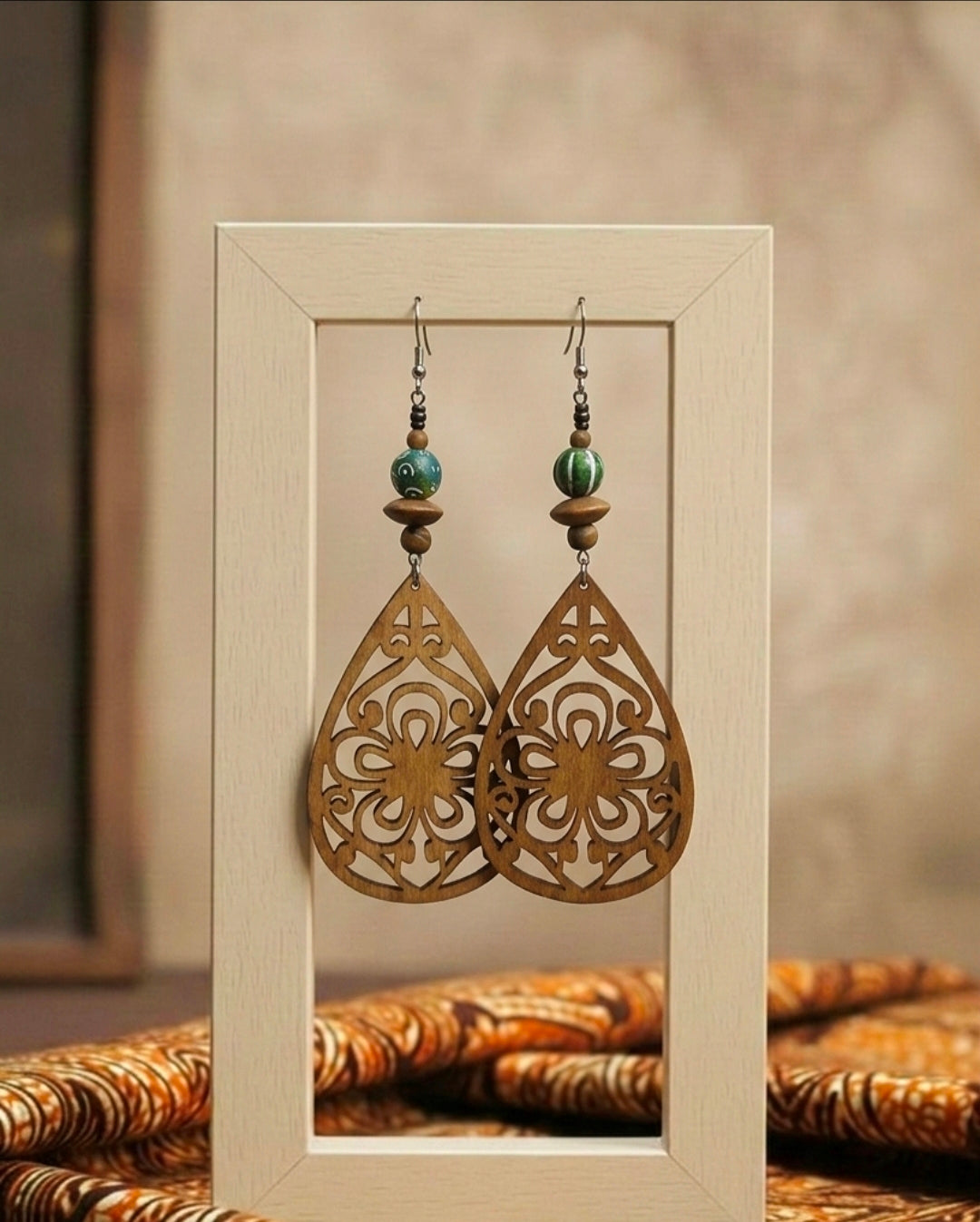 Pair of ornate wooden earrings with beads in a light frame.