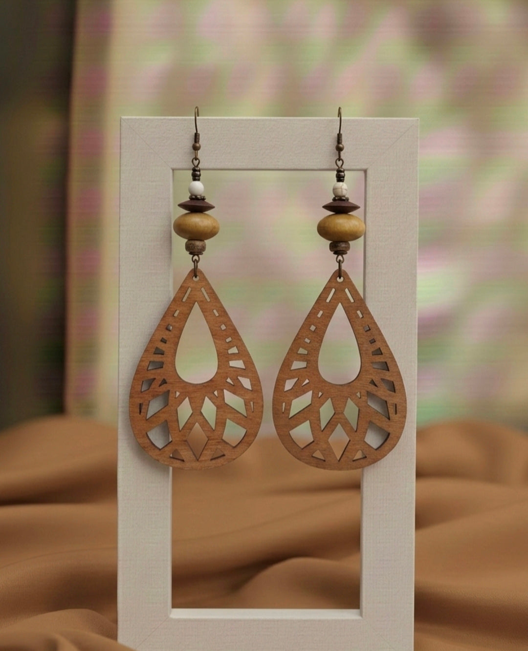Wooden earrings with intricate designs on a white card against a blurred background