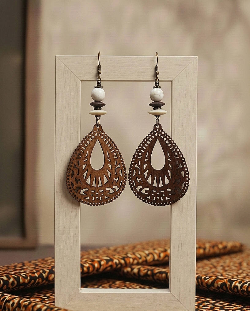Pair of ornate earrings on a wooden stand with a blurred background