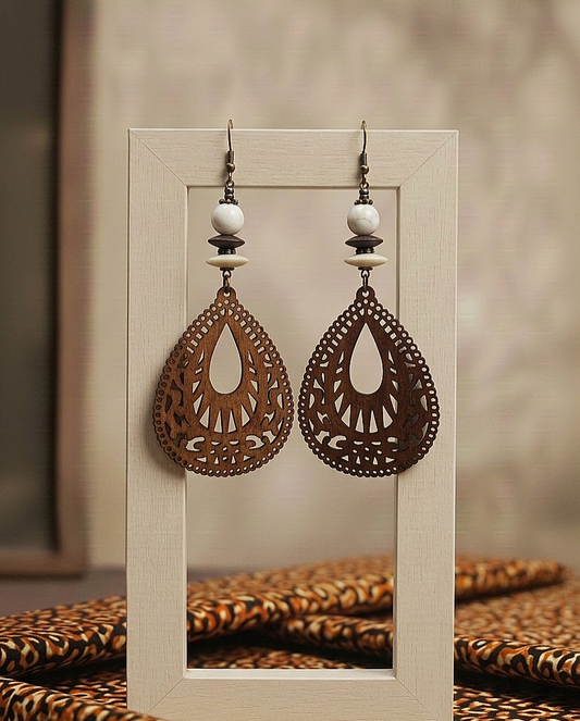 Pair of ornate earrings on a wooden stand with a blurred background