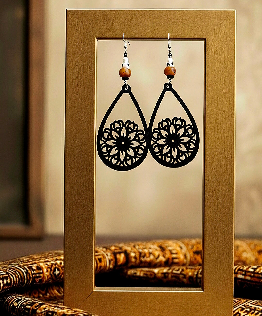 Black floral earrings on a gold display card with a blurred background