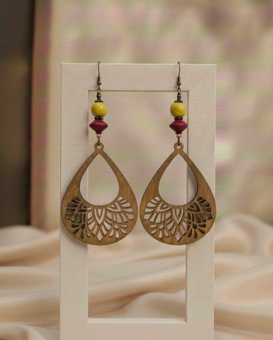 Pair of gold earrings with floral cut-out design on a beige background