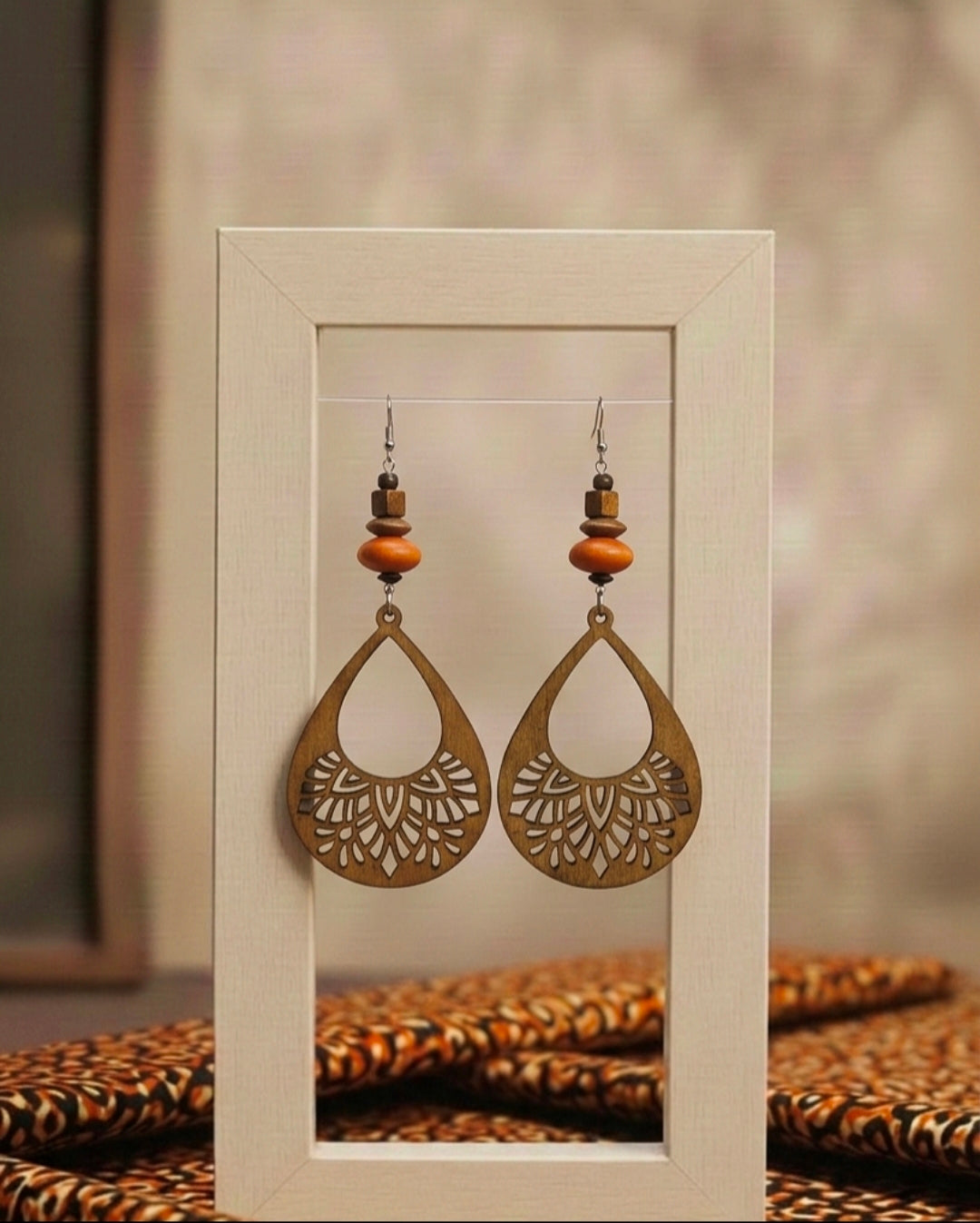 Pair of ornate earrings displayed in a white frame against a neutral background