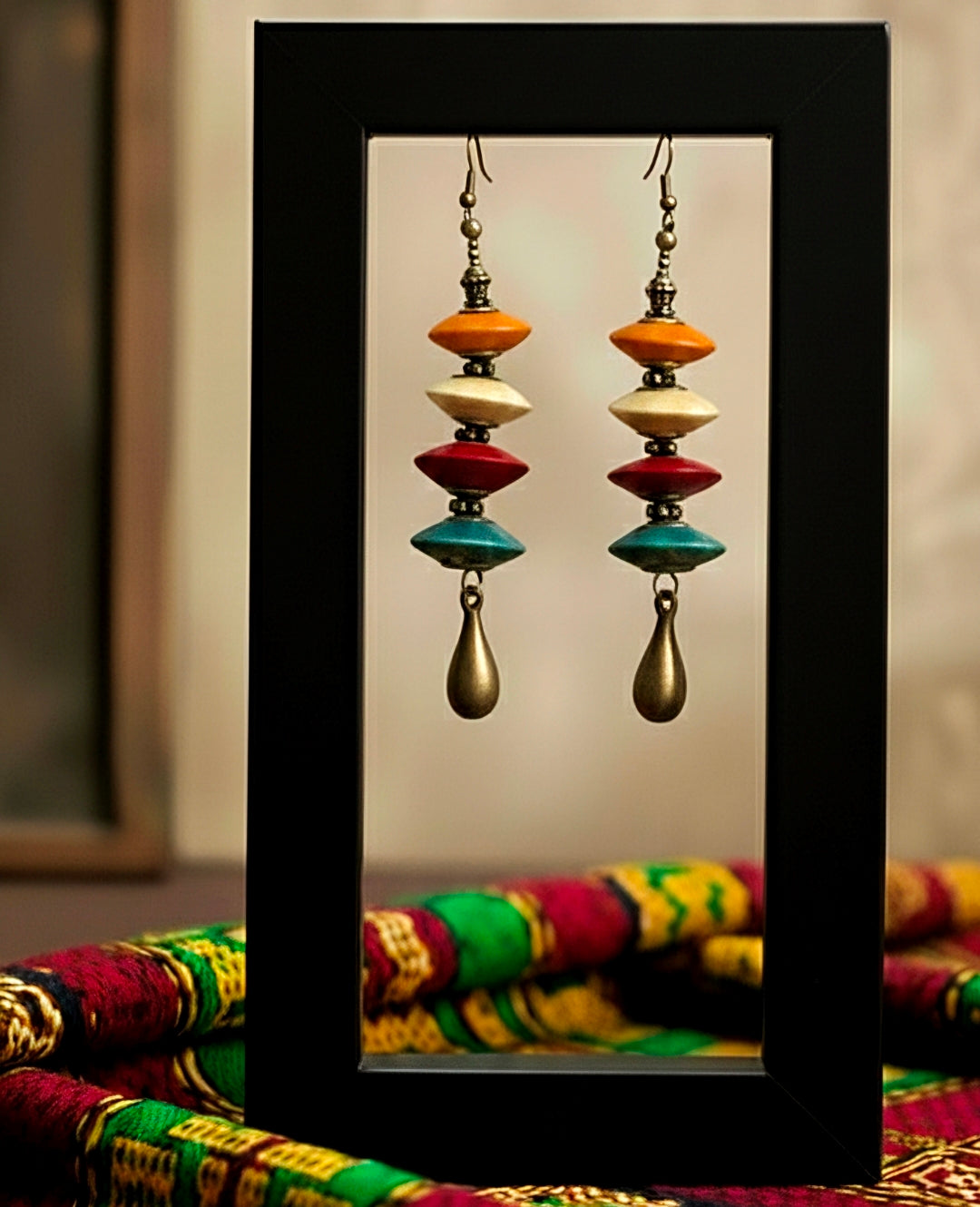 Colorful wood earrings with a black frame on a colorful fabric background