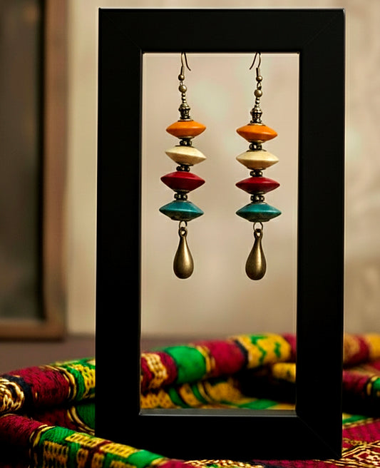 Colorful wood earrings with a black frame on a colorful fabric background