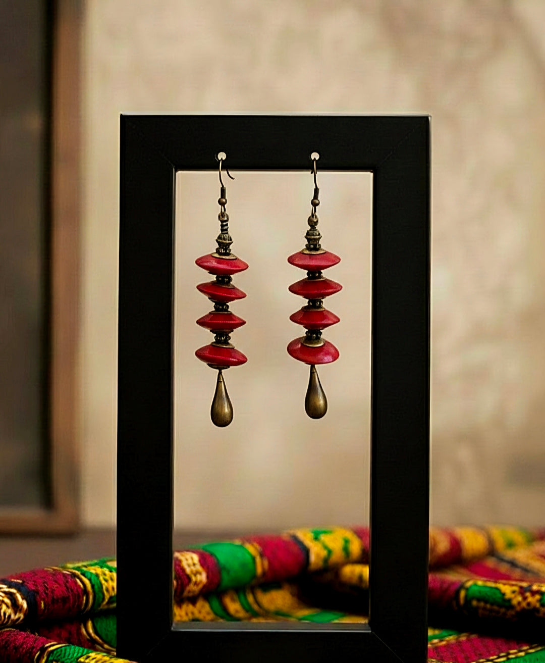 Pair of red and gold earrings displayed against a neutral background