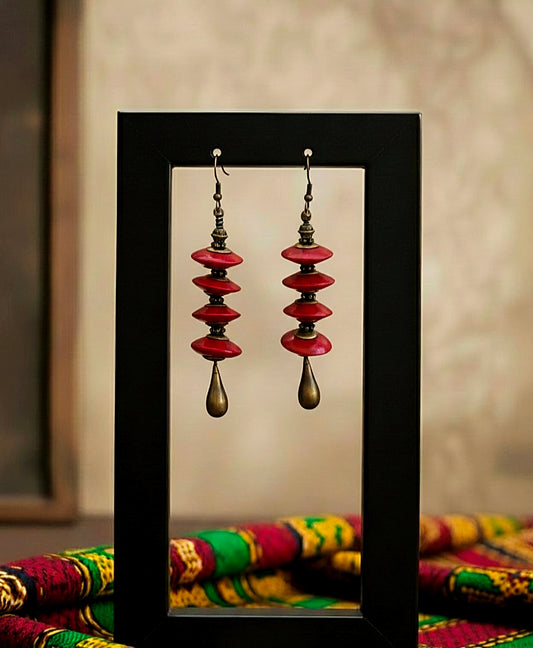 Pair of red and gold earrings displayed against a neutral background