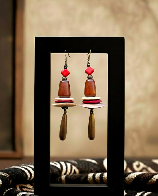 Pair of earrings with red and brown beads on a black stand against a neutral background