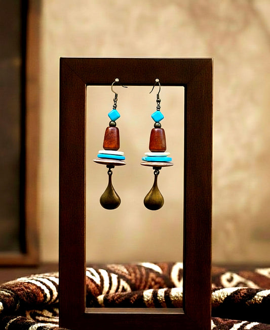 Pair of earrings with wooden and turquoise beads displayed in a wooden frame.