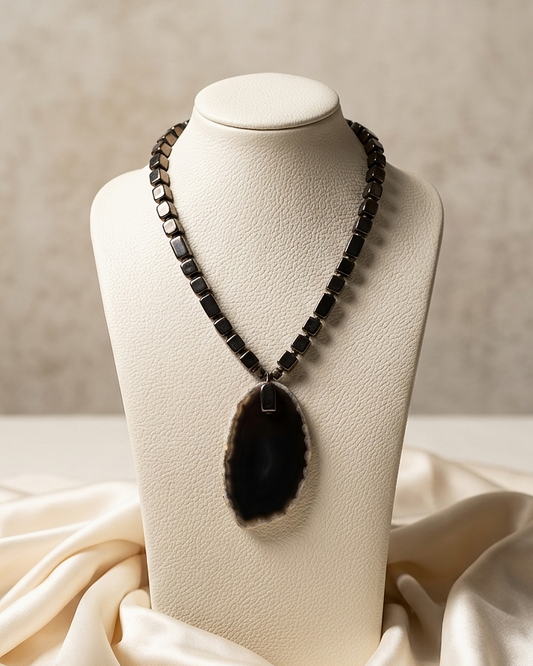 Necklace with a large pendant on a mannequin bust against a neutral background