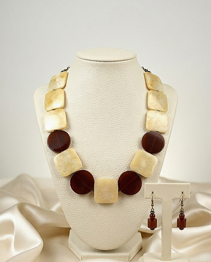 Necklace with square and round brown and beige beads on a mannequin bust with matching earrings.