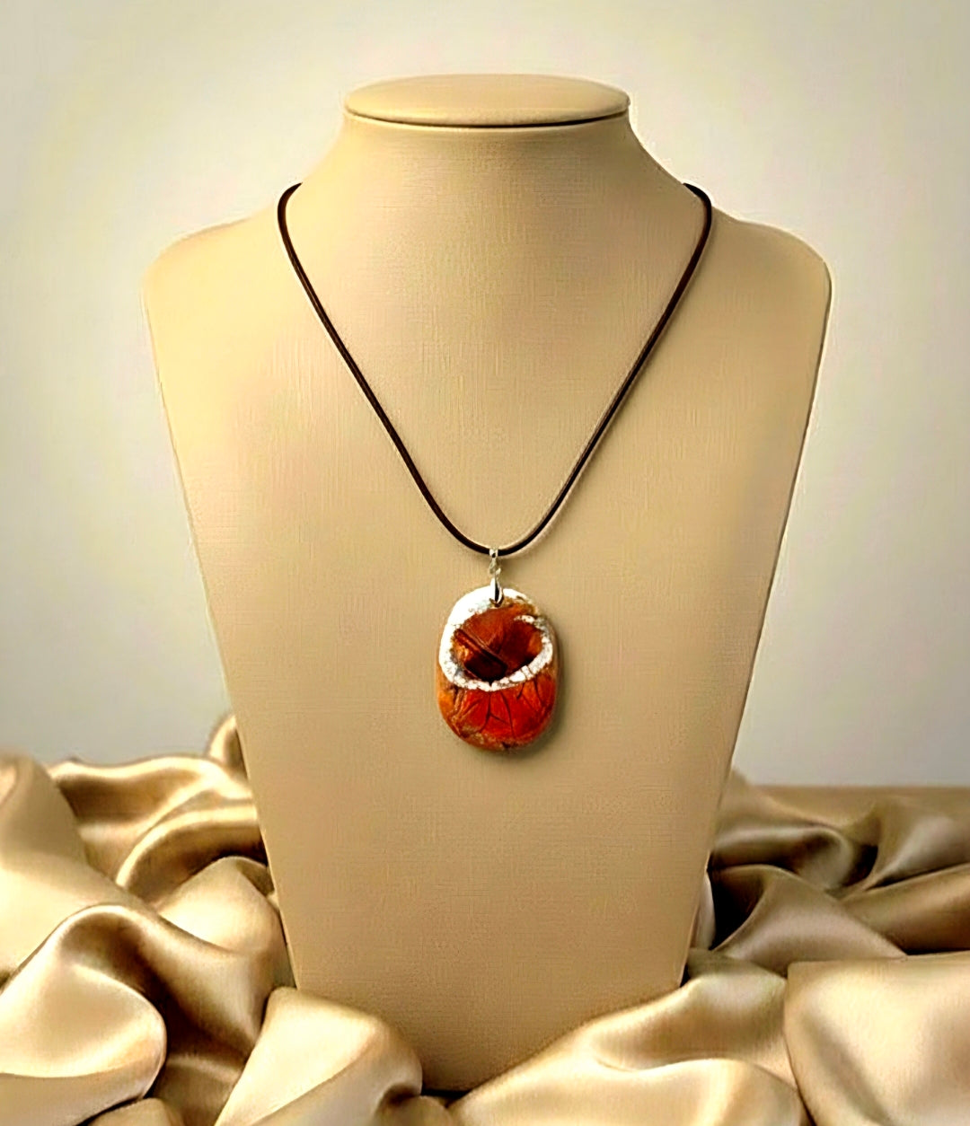 Necklace with a red pendant on a mannequin bust against a beige fabric background