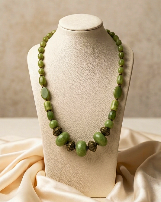 Green beaded necklace on a mannequin bust with a beige background
