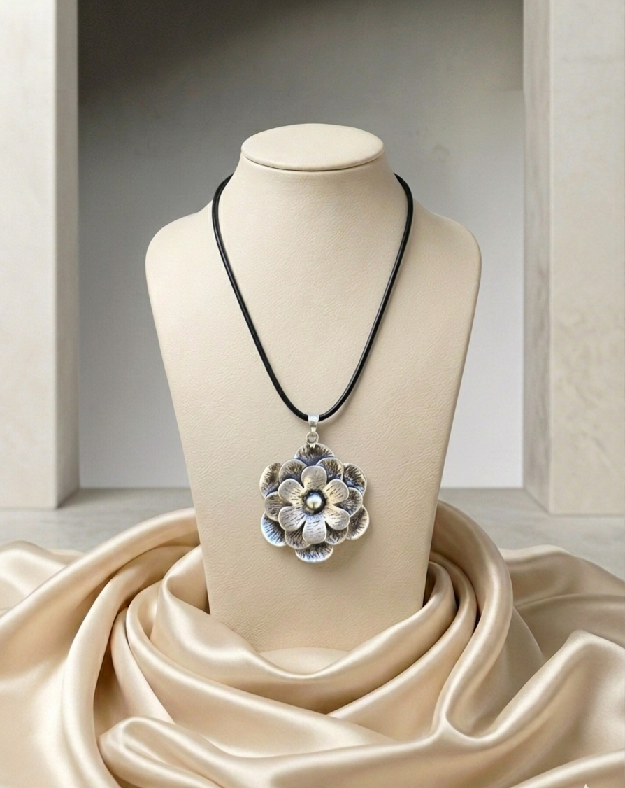 Necklace with a floral pendant on a mannequin bust draped with beige fabric.